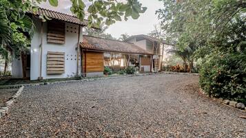 A residential property with a gravel driveway, wooden shutters, and a tiled roof.
