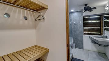 A bathroom with a wooden bench, a ceiling fan, and a modern sink.