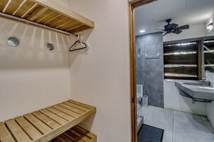 Un baño con un banco de madera, un ventilador de techo y un lavamanos moderno.