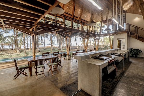 A spacious kitchen with a long counter, wooden chairs, and a view of the outdoors.
