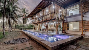 A modern house with a pool, outdoor furniture, and palm trees.