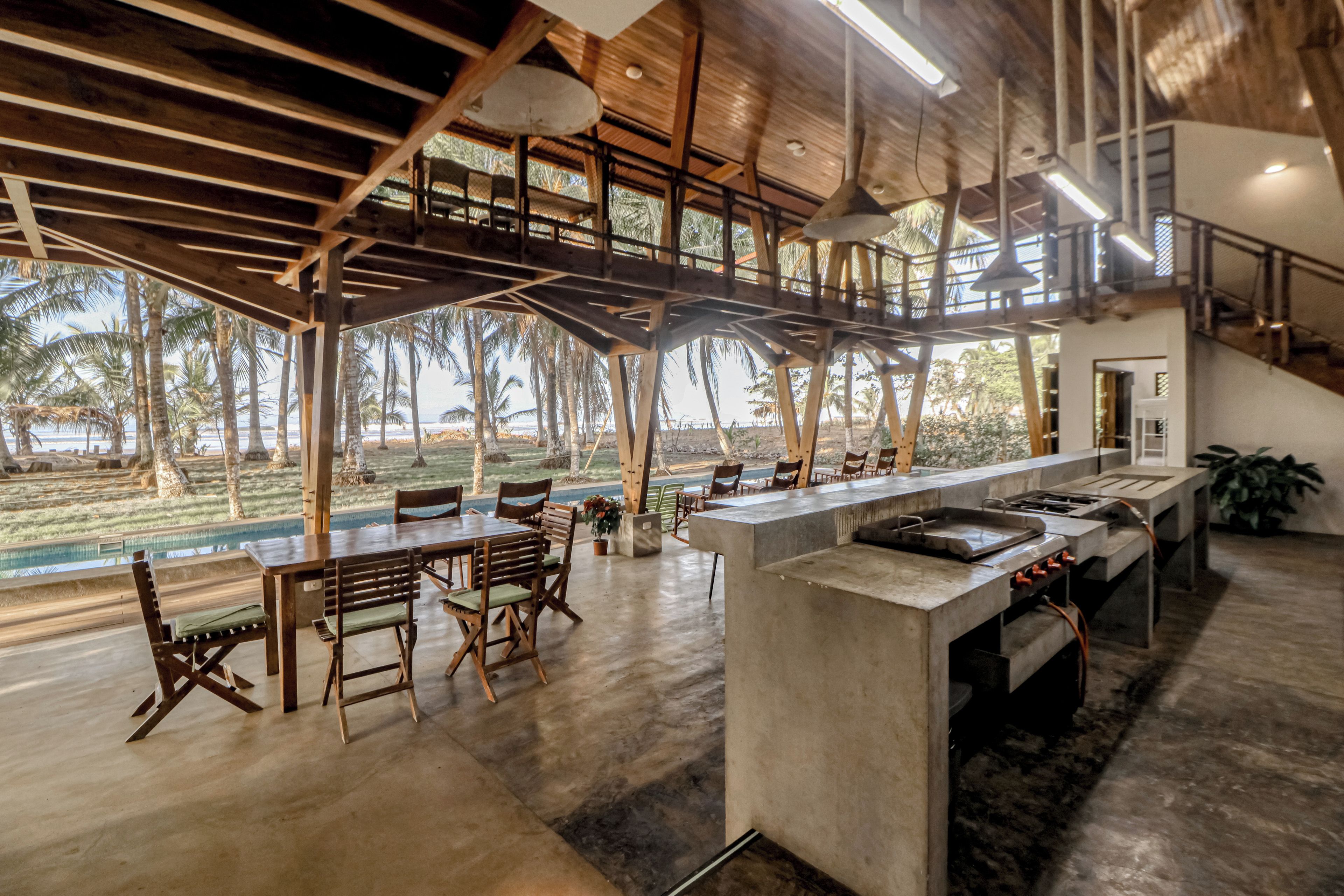 Una cocina amplia con una encimera larga, sillas de madera y vistas al exterior.