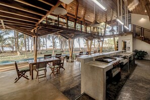 A spacious kitchen with a long counter, wooden chairs, and a view of the outdoors. - Award-winning Oceanfront Home w/ Pool & Hot Tub! (Bejuco)