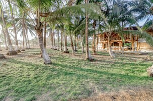 Un resort tropical con palmeras, un césped y un edificio de madera con balcón.