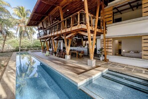 A poolside area with a wooden deck, lounge chairs, and a covered seating area.