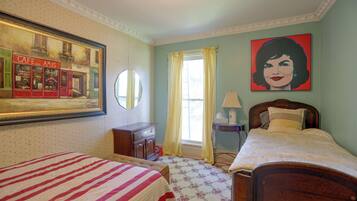 A bedroom with two beds, a dresser, a mirror, a window with curtains, and a painting on the wall.