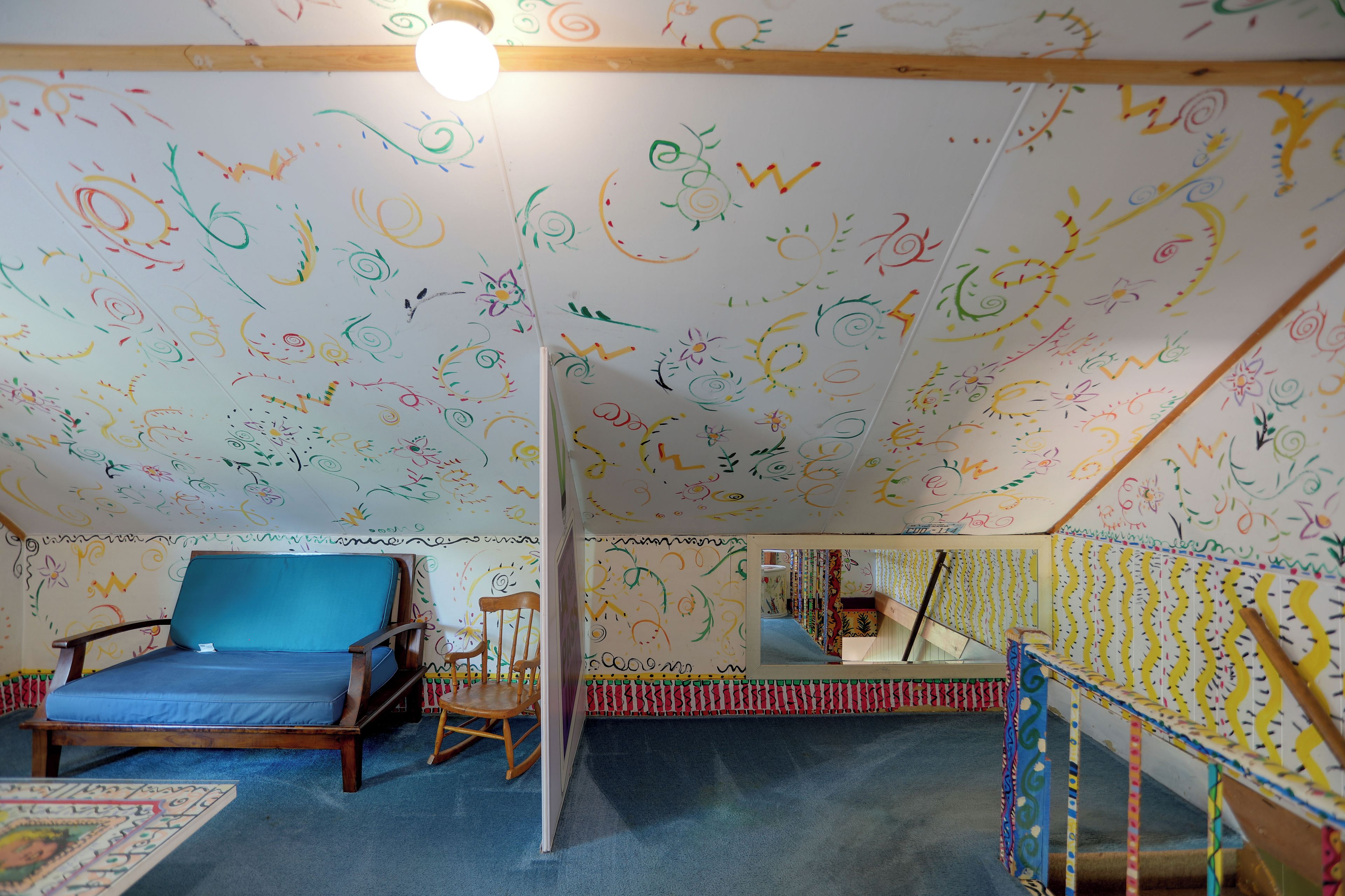 Una habitación con un sofá azul, una mecedora de madera y una alfombra estampada.