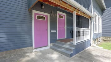 A two-story house with a front porch, a pink door, and a mailbox.