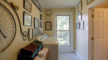A laundry room with a washing machine, a drying rack, and a window with a view of trees.