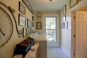A laundry room with a washing machine, a drying rack, and a window with a view of trees. - Downtown Spacious 5BR w/ Game Room (Ellicottville)