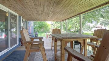 A wooden deck with a table and chairs, a covered area with a view of the outdoors, and a building with a sign that reads 'EVL'.