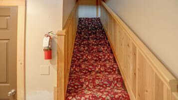 A narrow staircase with a wooden handrail and carpeted steps.