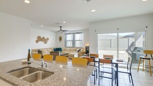 Una cocina moderna con encimeras de granito, un lavaplatos integrado y un comedor con mesa y sillas.