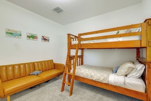 Una cama litera con escalera, un sofá y dos adornos de pared.