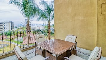 Un balcón con mesa y sillas, con vistas a una zona residencial con edificios y árboles.