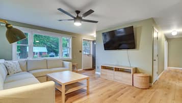 A living room with a sofa, coffee table, TV, and a ceiling fan.