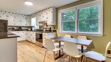 A modern kitchen with white cabinets, stainless steel appliances, and a dining area with a table and chairs.