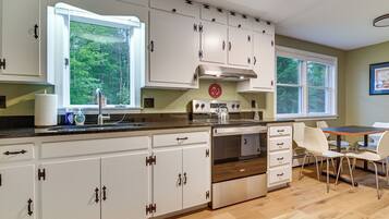 A kitchen with white cabinets, a stove, and a dining area with a table and chairs.