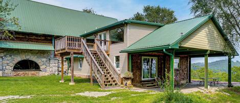 A two-story building with a green roof, a stone archway, and a covered porch with picnic tables.