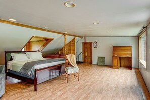 Un dormitorio con una cama de madera, una silla, un escritorio de madera y una escalera.