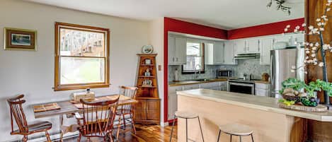 A kitchen with wooden flooring, a dining area with a table and chairs, and a bar area with stools.