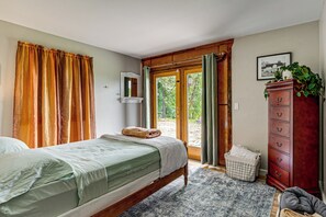 Un dormitorio con una cama, un aparador de madera, un espejo y una ventana con cortinas.