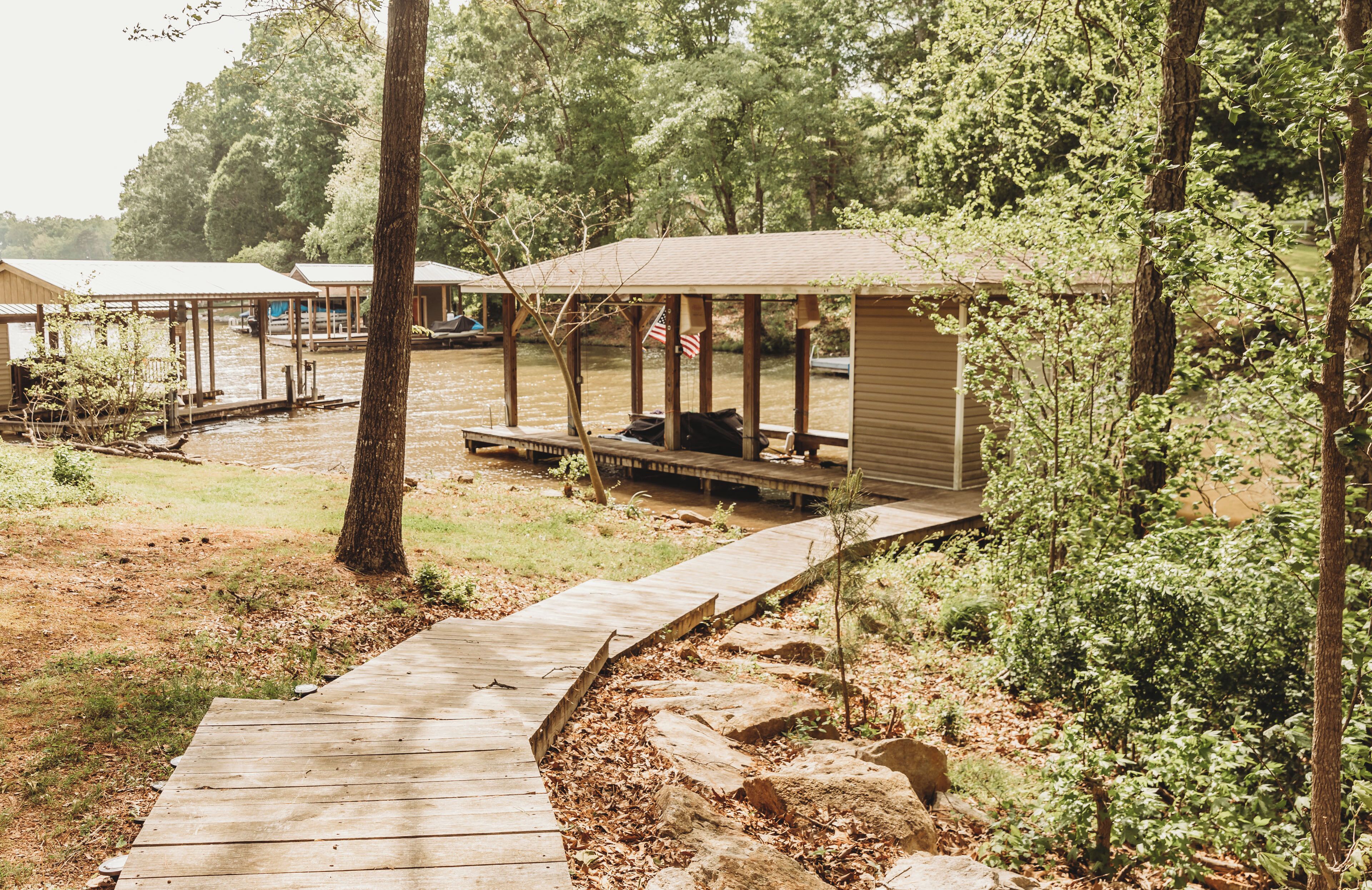 A wooden deck leading to a covered outdoor seating area with a view of a water body.