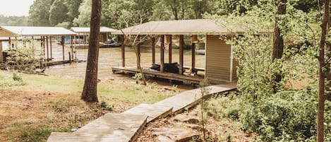 A wooden deck leading to a covered outdoor seating area with a view of a water body.