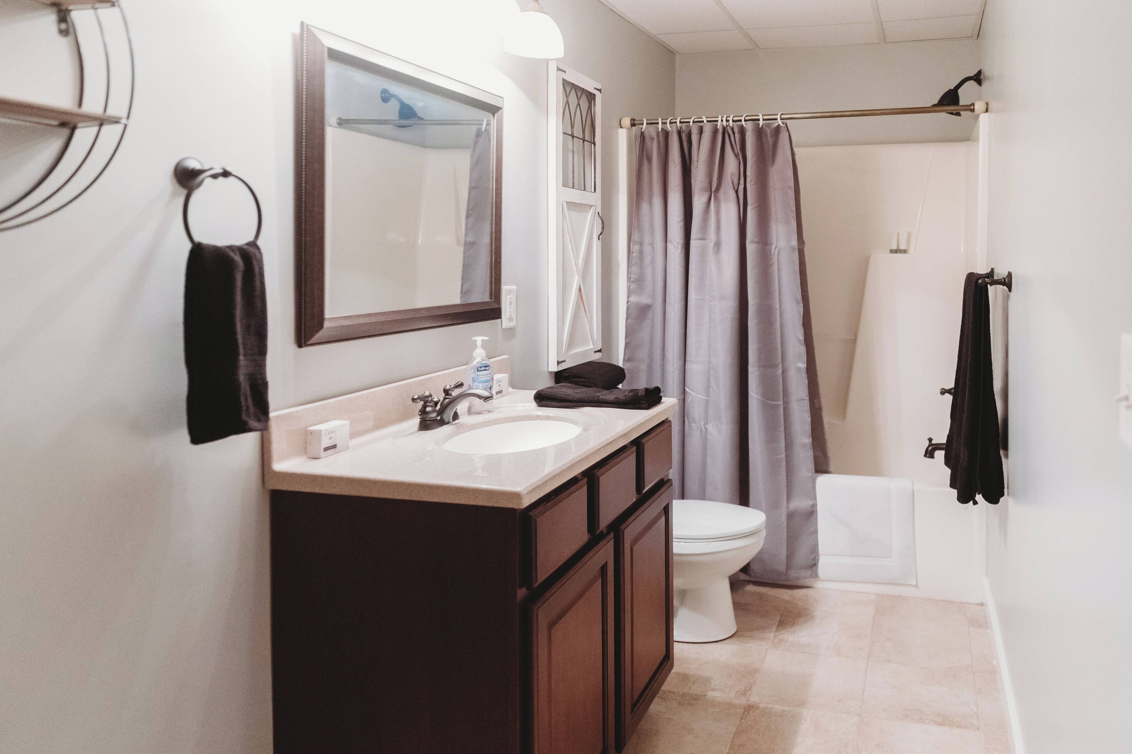 A bathroom with a sink, mirror, toilet, and shower curtain.