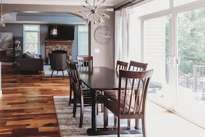 Uma sala de jantar com mesa e cadeiras de madeira escura, lareira e vista para o exterior.