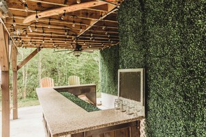 Un área de bar al aire libre con techo de madera, ventilador de techo y pared verde.