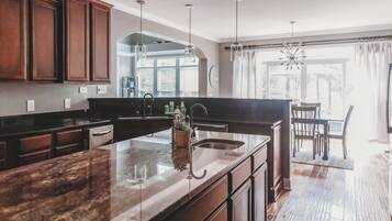 A modern kitchen with dark wooden cabinets, a granite countertop, and a large island with a sink.