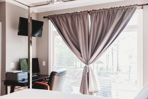 Une chambre d’hôtel équipée d’un lit, d’un bureau avec un ordinateur, d’une chaise et d’un téléviseur fixé au mur.