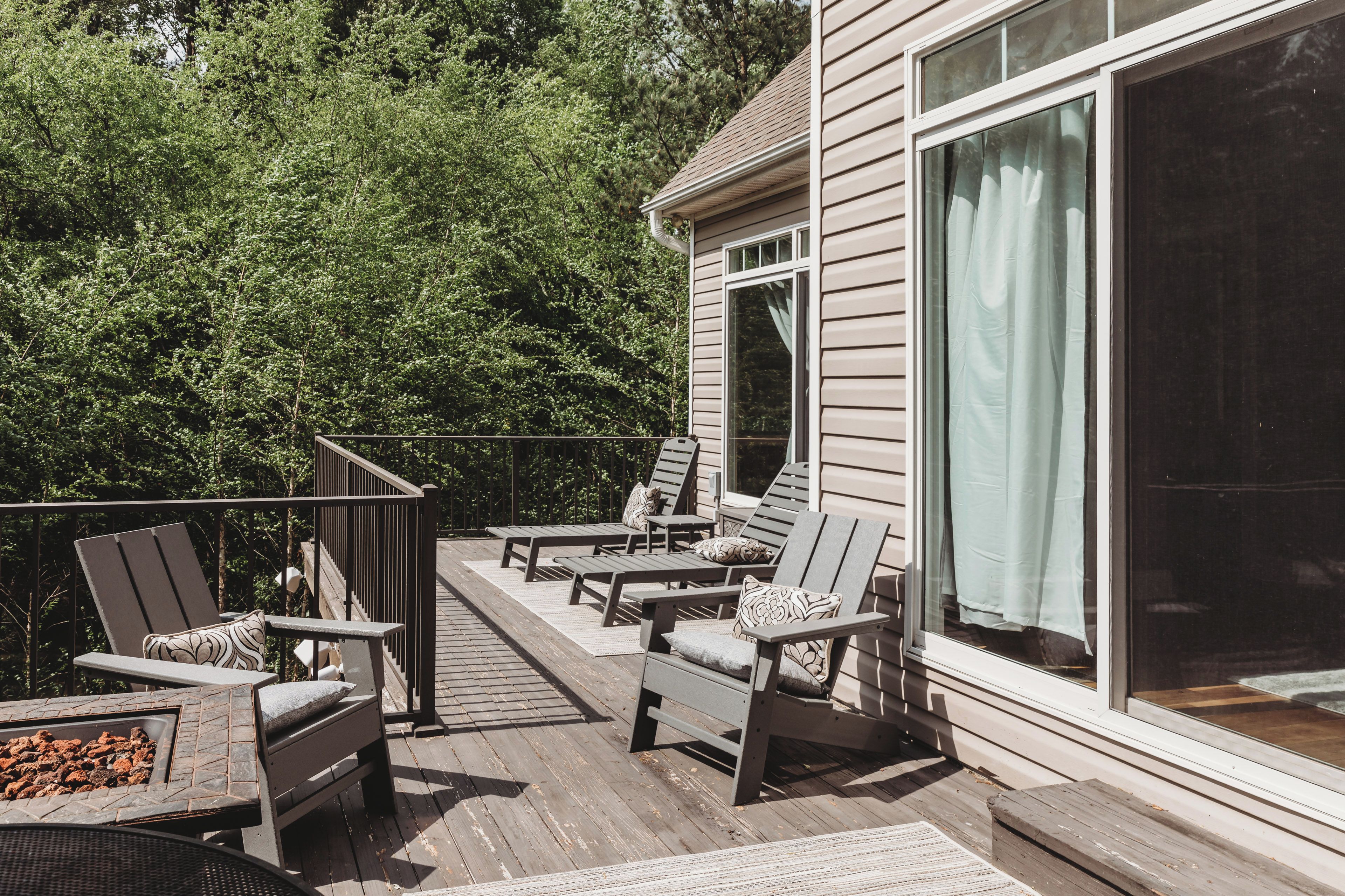 A deck with outdoor furniture, a fire feature, and a view of a house with a sliding glass door.