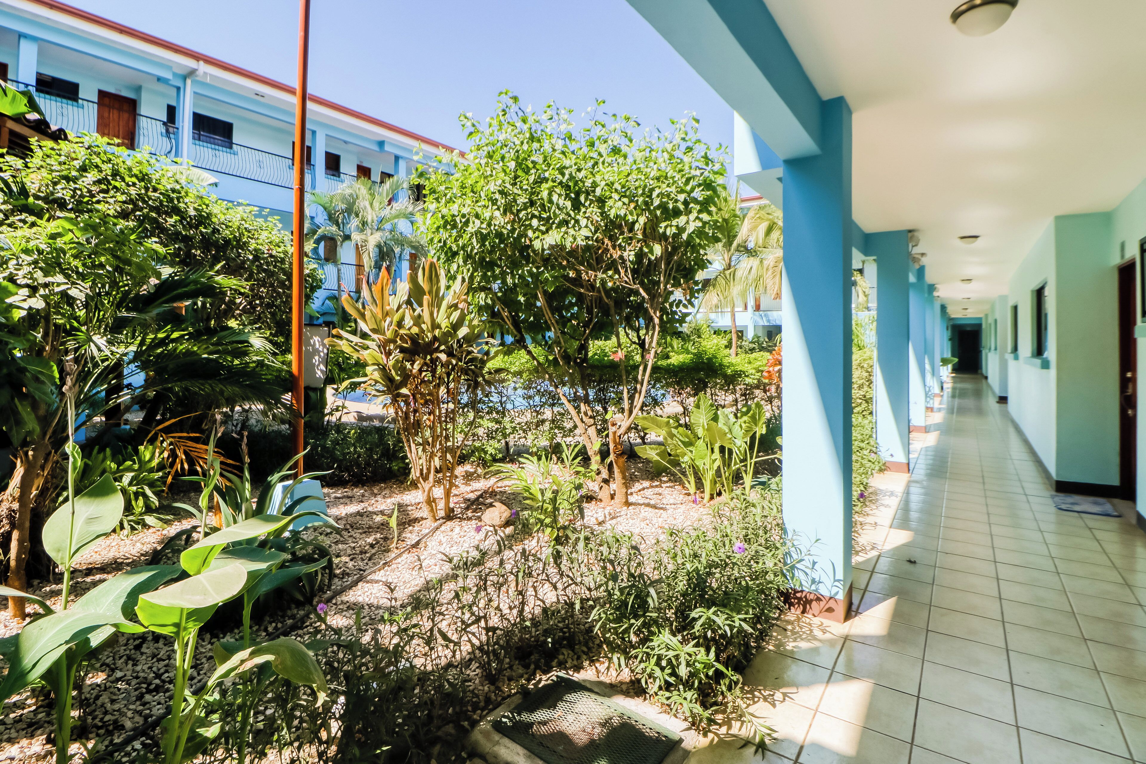 A corridor with a tiled floor leading to a building with a blue exterior.