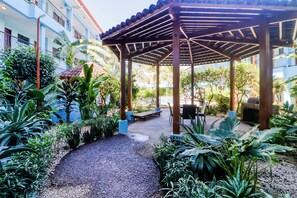 A covered outdoor area with a gravel path, seating, and lush greenery. - Pool, Walk to Beach: Playas del Coco Studio (Sardinal)