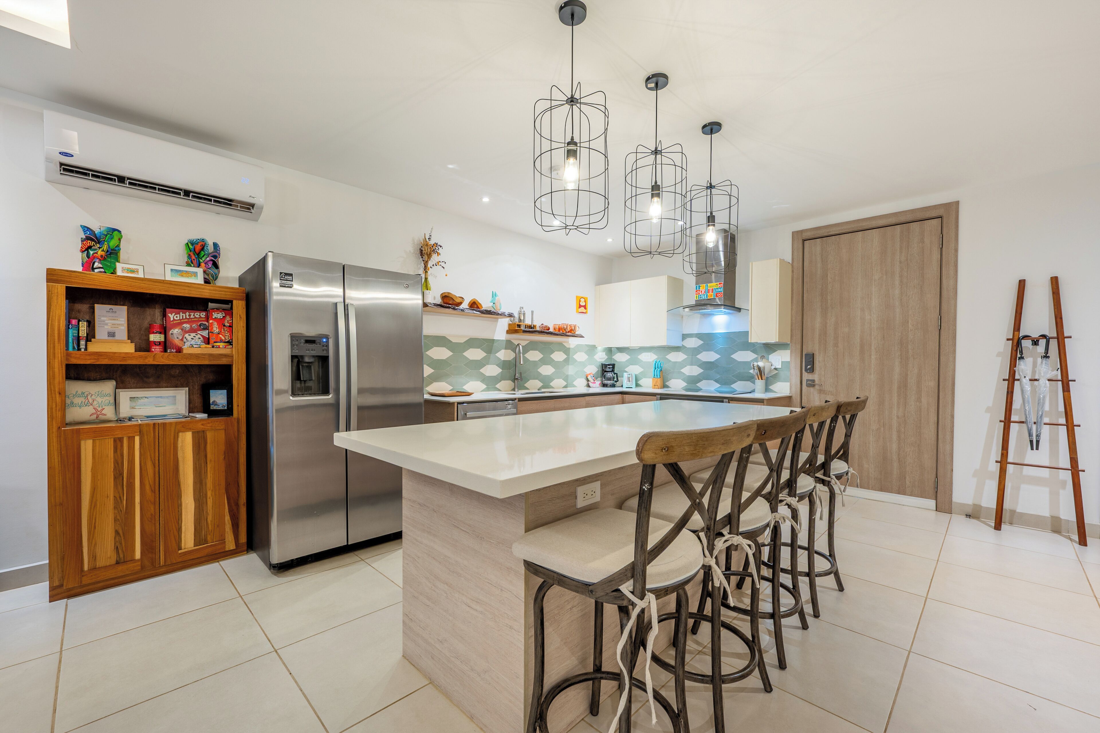 A modern kitchen with a central island, stainless steel appliances, and a wooden bar stool seating area.
