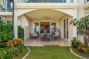 Ein überdachter Patio-Bereich mit Esstisch und Stühlen, umgeben von Grünpflanzen und einem kleinen Garten.