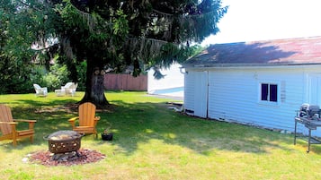 A backyard with a large tree, a wooden deck, and a white shed.