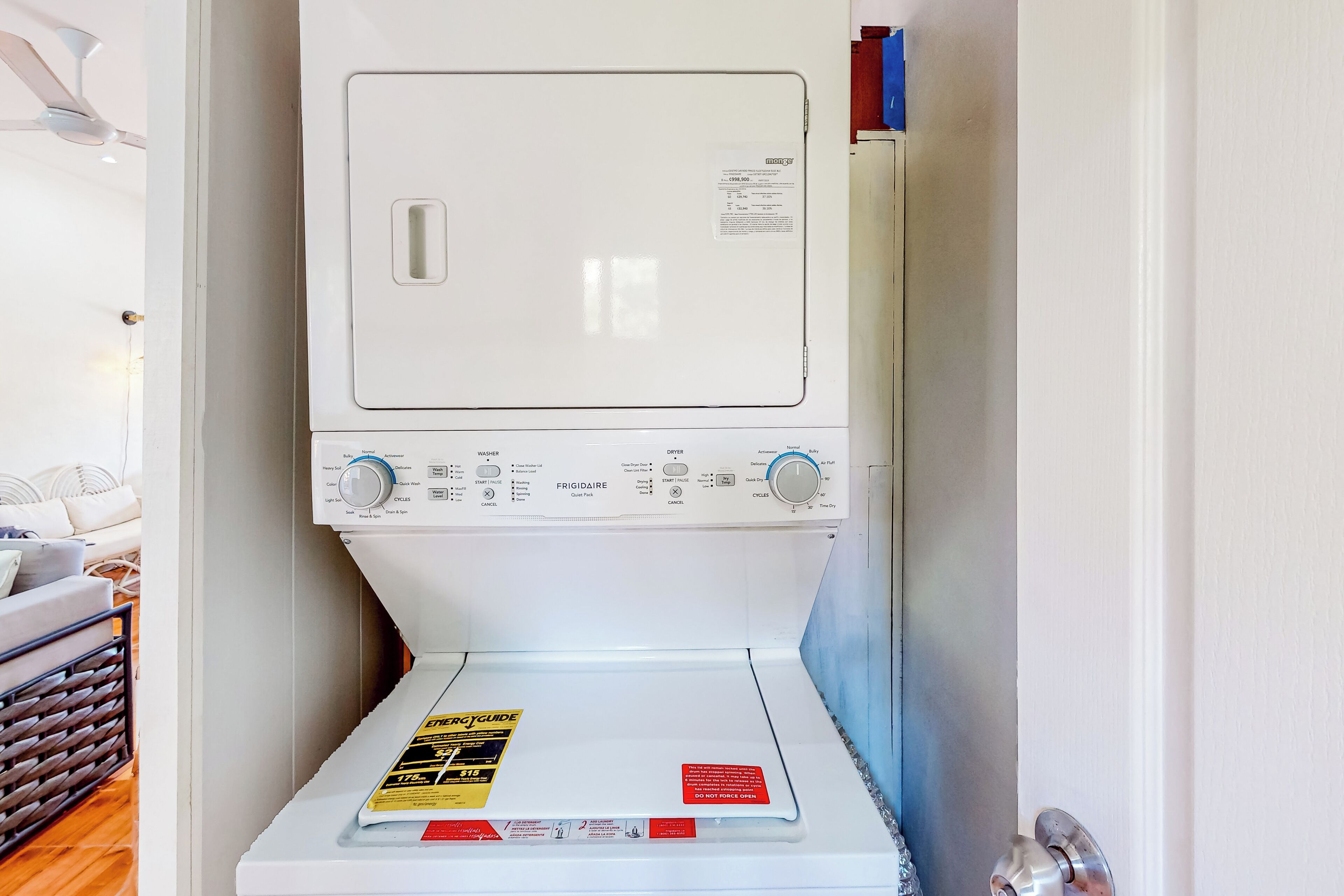 Vue de face d’un lave-linge blanc, avec son panneau de commande, un guide d’utilisation de la lessive et une étiquette d’avertissement.