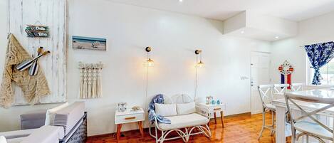 Une pièce lumineuse avec un plancher en bois, des meubles blancs et des lampes fixées au mur.