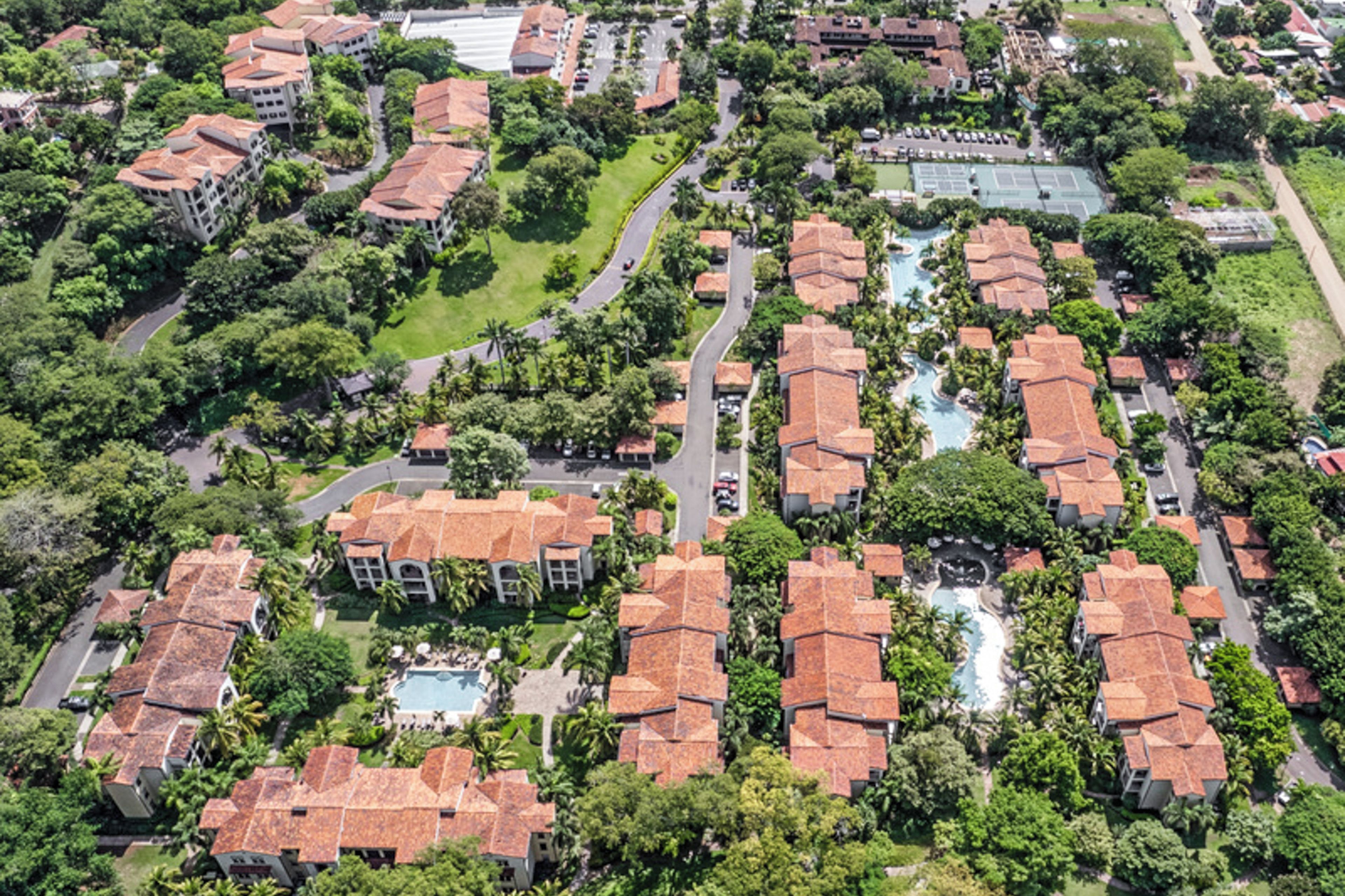 Vista aérea de una zona residencial con varios edificios, carreteras y zonas verdes.