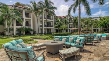 A resort with outdoor seating, palm trees, and a pool.
