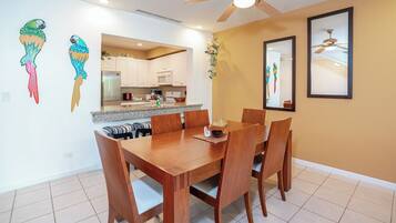 Un comedor con mesa y sillas de madera, una cocina al fondo y decoración en la pared.