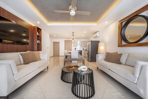 A modern living room with a sofa, coffee table, and a dining area. - Ocean-view Tamarindo: Community Pool Access (Tamarindo)
