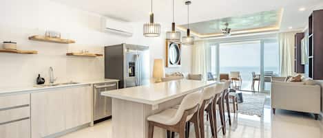 Une cuisine moderne dotée d’un îlot central, de tabourets de bar et de luminaires suspendus.