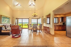 A spacious living area with a view of the countryside, a dining set, and a kitchen with wooden cabinets. - Lake & Volcano Views: 2-unit Retreat w/ Hot Tub! (Tronadora)
