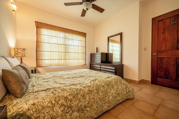 A bedroom with a bed, a dresser, a mirror, a ceiling fan, and a door. - Lake & Volcano Views: 2-unit Retreat w/ Hot Tub! (Tronadora)