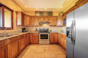 A kitchen with wooden cabinets, stainless steel appliances, and a granite countertop. - Lake & Volcano Views: 2-unit Retreat w/ Hot Tub! (Tronadora)