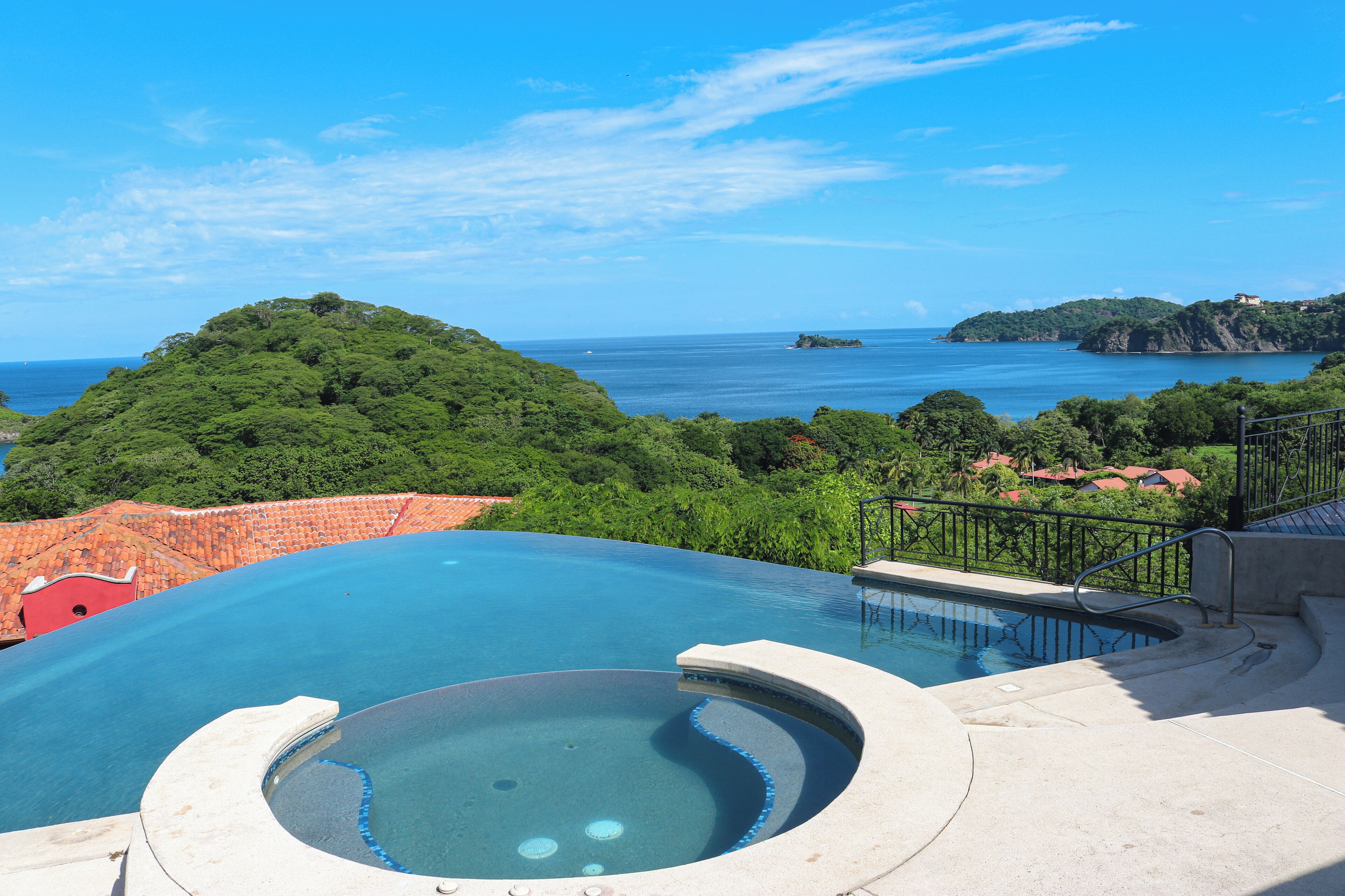 Une piscine avec vue sur la mer et une colline.